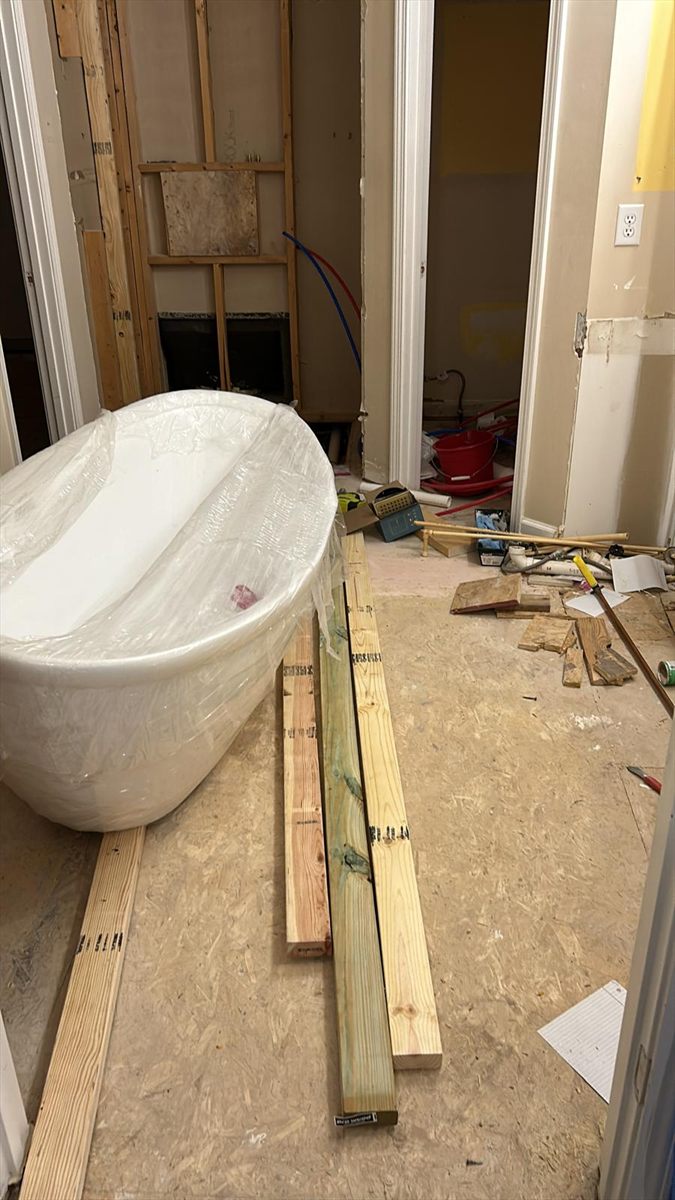 The freestanding tub, still wrapped, staged on the subfloor before setting
