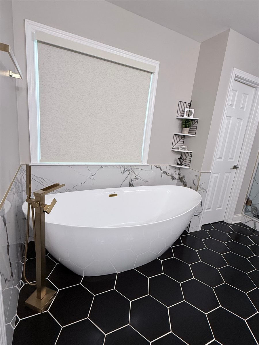 Freestanding tub under the window, with a brushed gold floor mount filler