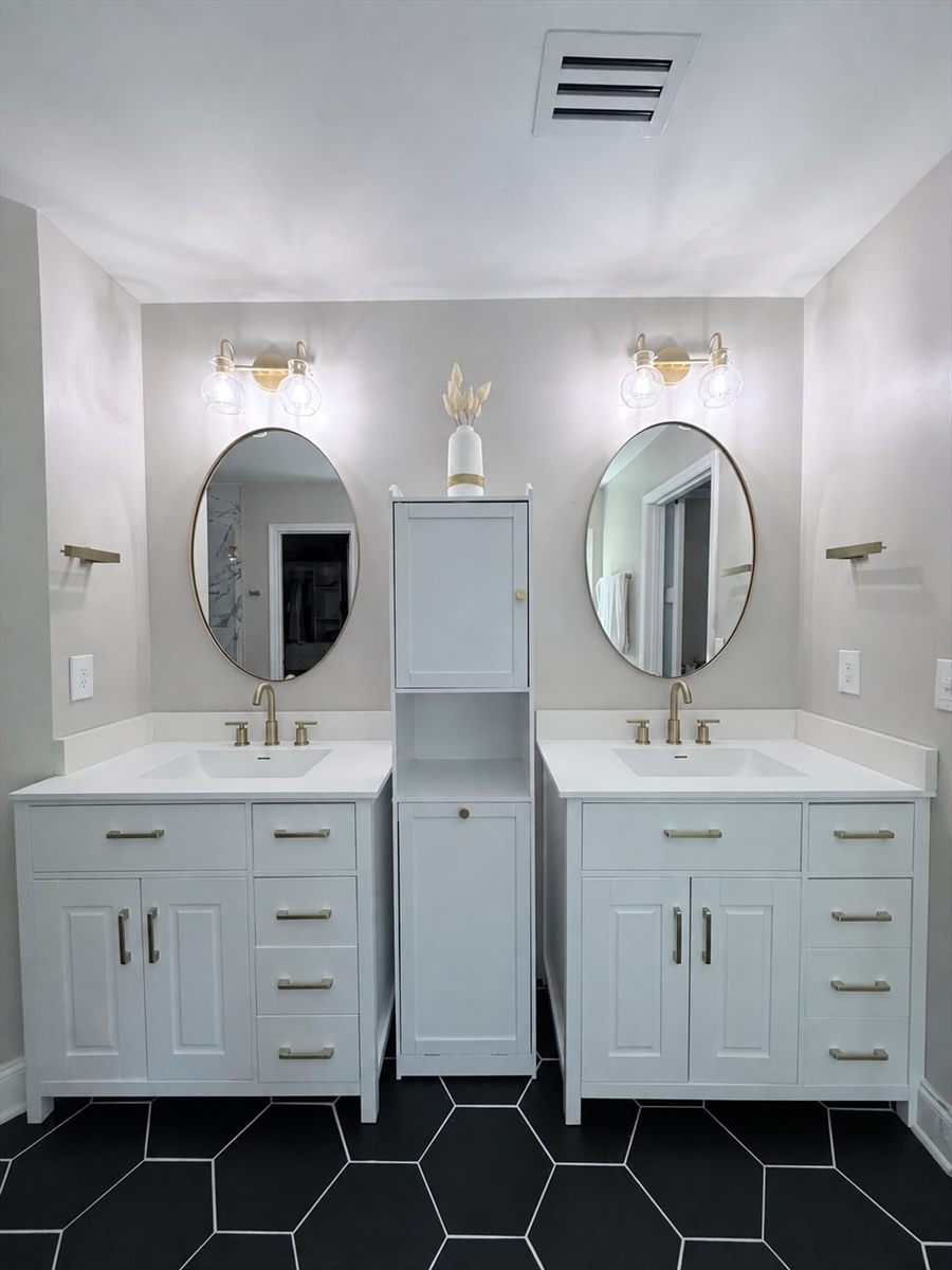 Double vanity with round mirrors and a tall linen cabinet between the sinks