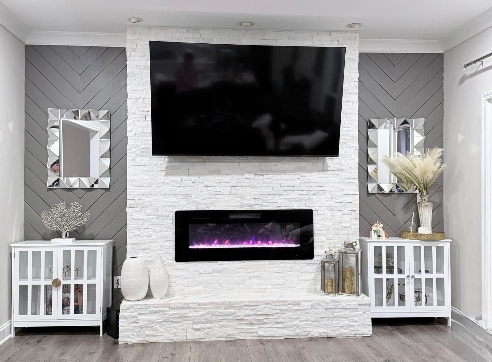 Living room after renovation, floor to ceiling white stacked stone fireplace with a linear insert and grey chevron panelled walls