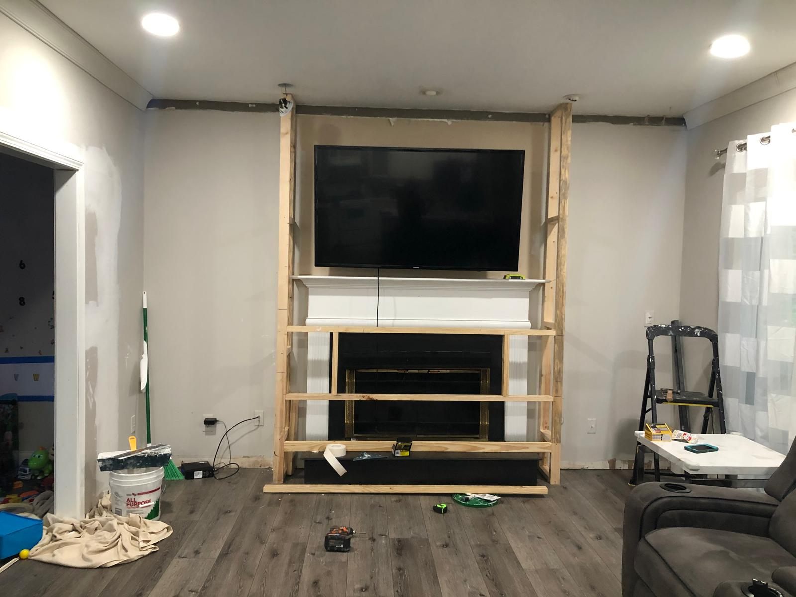 The same living room before renovation, original white mantel and brass fireplace surround with framing started