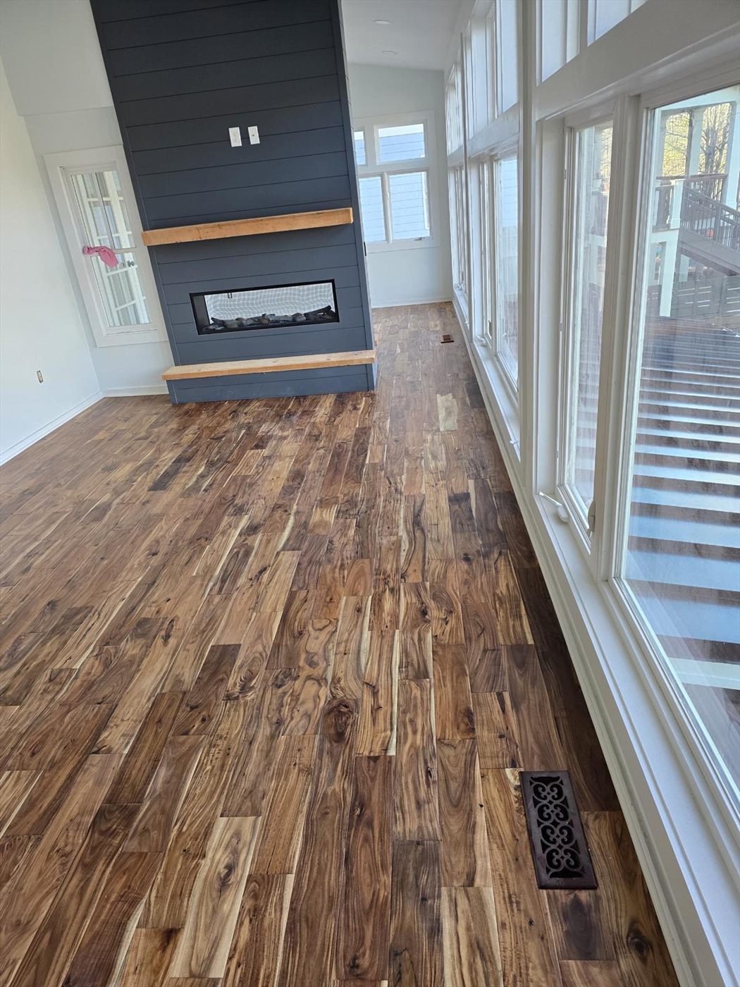 Great room with a charcoal shiplap fireplace surround, timber mantel and wide plank acacia flooring