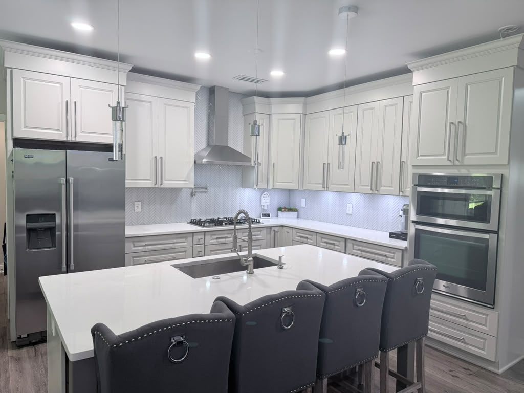 Renovated kitchen with painted cabinetry, quartz island and stainless double ovens