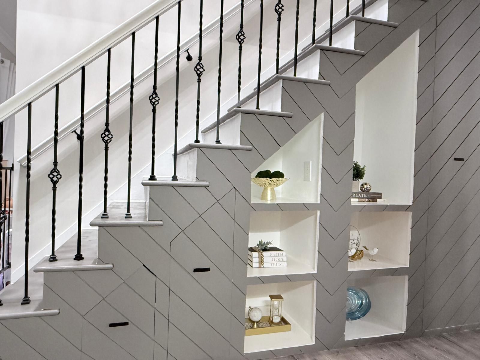Chevron panelled staircase wall with built in niches and iron balusters