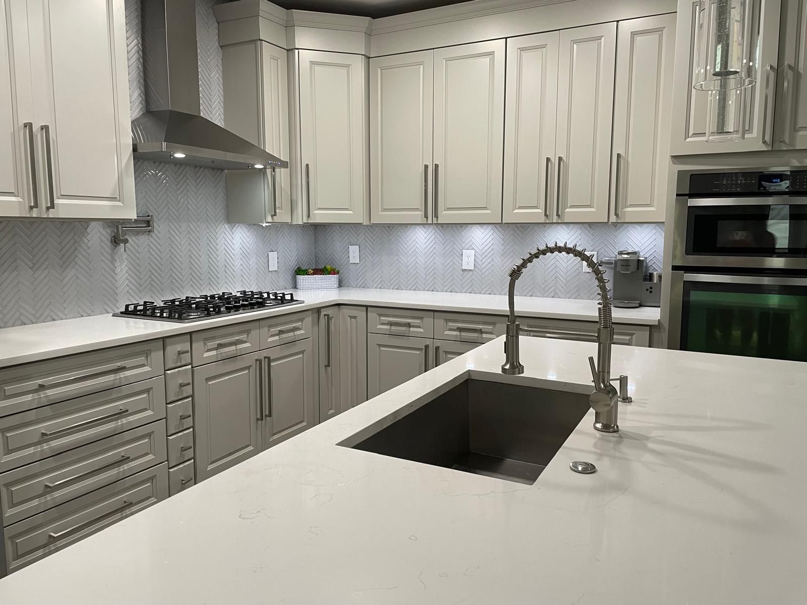 Remodeled kitchen with quartz island, undermount sink and herringbone tile backsplash