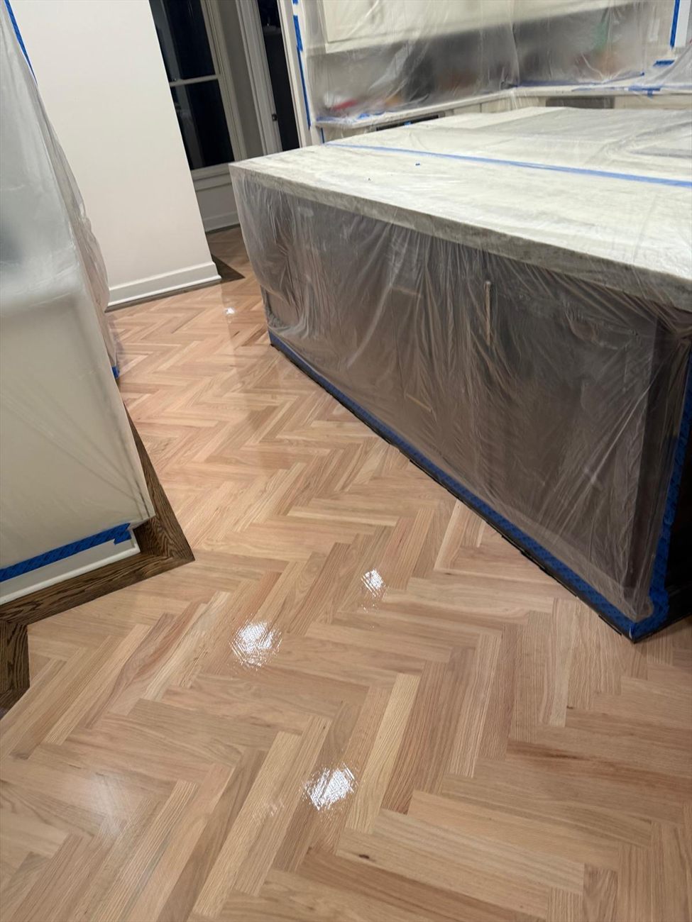 Finished herringbone floor with the kitchen island and cabinetry sealed in protective sheeting and tape